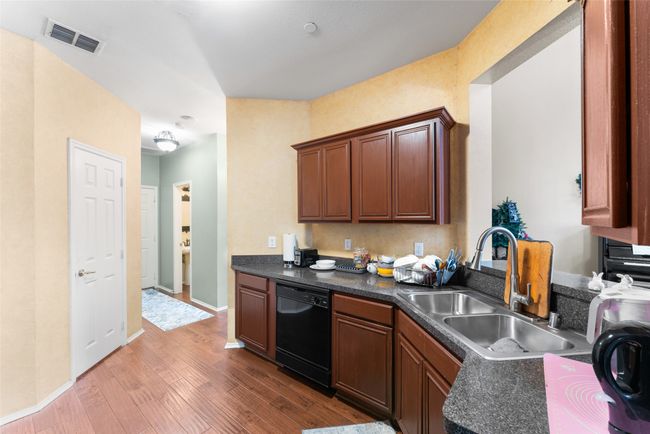 Kitchen featuring a sink, dark countertops, visible vents, dishwasher, and wood finished floors | Image 12
