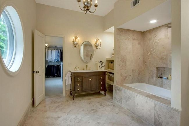 Bathroom with a notable chandelier, tiled bath, vanity, and tile flooring | Image 22