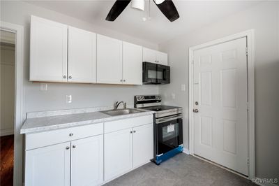 Kitchen with ceiling fan, white cabinets, sink, and stainless steel electric range | Image 3