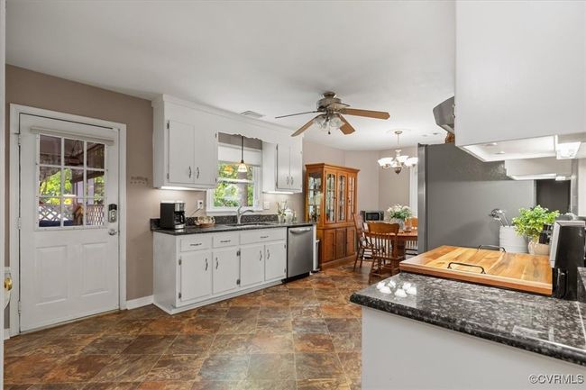 Kitchen with stainless steel appliances, a ceiling fan, stone finish floors, white cabinets, and baseboards | Image 12