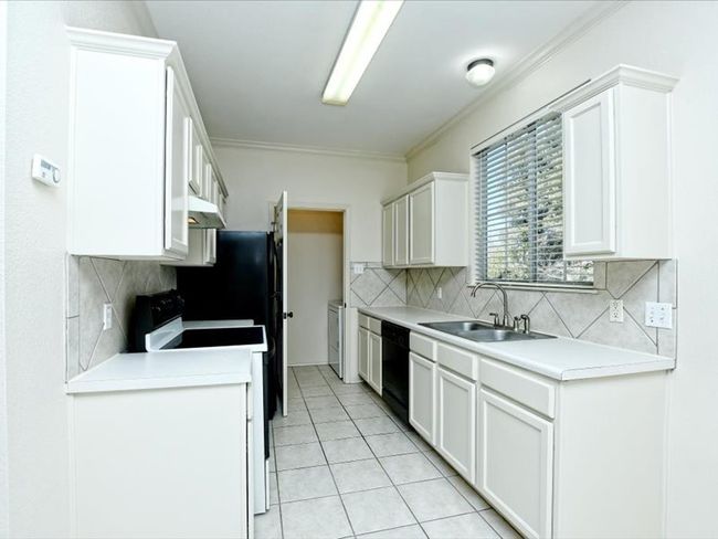 Kitchen with light countertops, light tile patterned floors, a sink, electric range oven, and black dishwasher | Image 9