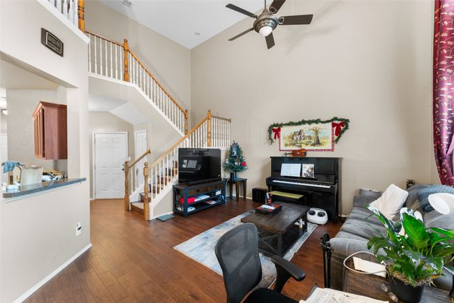 Living area featuring visible vents, stairs, a towering ceiling, a ceiling fan, and dark wood finished floors | Image 8