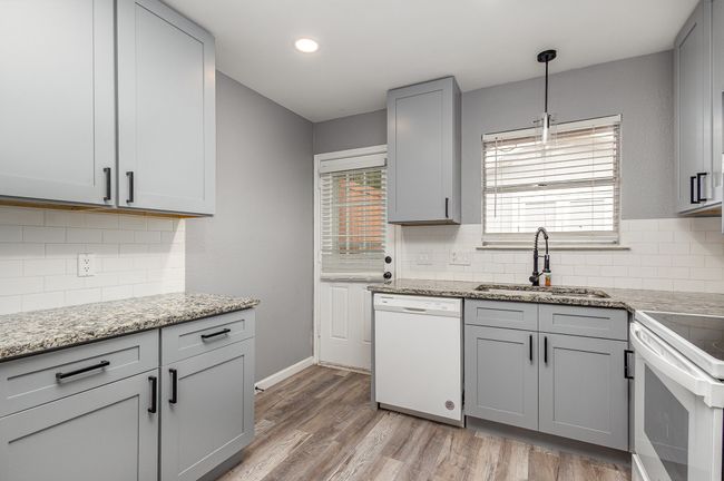 Kitchen with a sink, white appliances, gray cabinets, backsplash, and light wood-style floors | Image 18