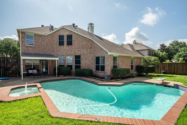 View of swimming pool featuring a fenced backyard, a patio, a diving board, and a pool with connected hot tub | Image 38