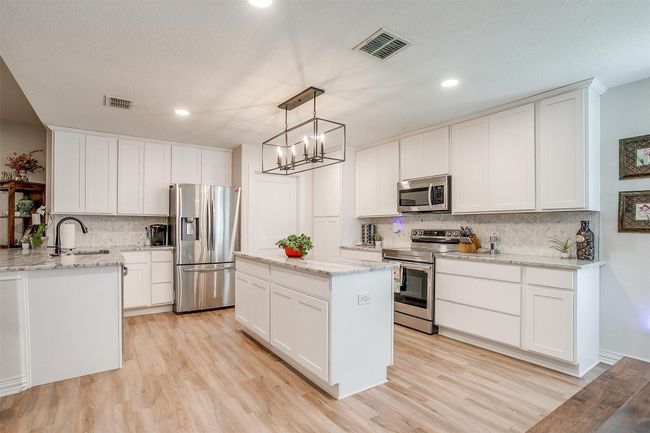 Kitchen featuring appliances with stainless steel finishes, backsplash, light wood-style floors, light marble counters, and recessed lighting | Image 15