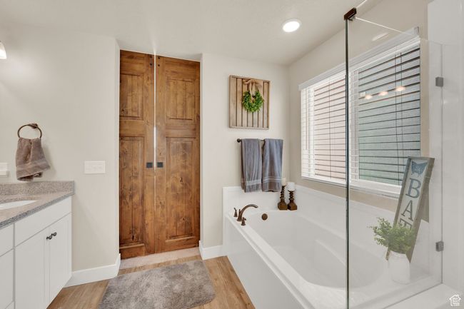 Full bath with wood finished floors, a bath, vanity, baseboards, and an enclosed shower | Image 23