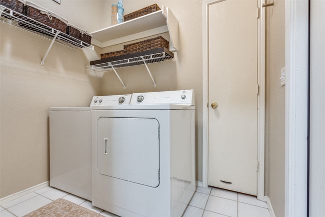 The utility room features a linen closet, shelves for storage and access to the 2 car garage. | Image 22