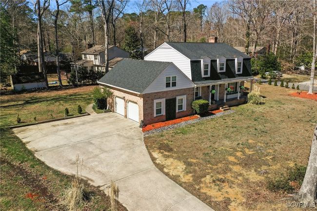 View of front of home with brick siding, an attached garage, a front lawn, covered porch, and driveway | Image 43