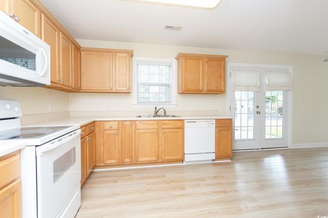 Kitchen with white appliances, a sink, light wood-style flooring, light countertops, and baseboards | Image 9