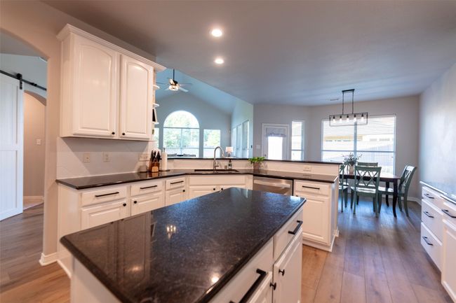 Kitchen featuring stainless steel dishwasher, light wood-style flooring, lofted ceiling, ceiling fan, and white cabinets | Image 16