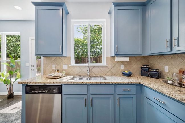 Kitchen with dishwasher, blue cabinetry, tasteful backsplash, a sink, and granite countertops | Image 15