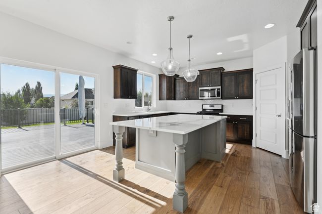 Kitchen with stainless steel appliances, a kitchen island, hardwood / wood-style flooring, decorative backsplash, and recessed lighting | Image 9