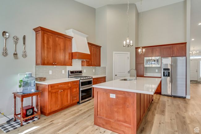 Kitchen with an inviting chandelier, a sink, light wood-style flooring, appliances with stainless steel finishes, and high vaulted ceiling | Image 10