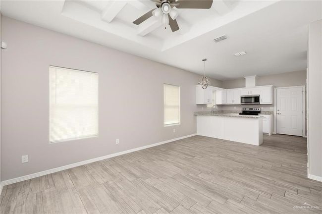 Kitchen with stainless steel appliances, ceiling fan, a peninsula, light wood-style flooring, and white cabinets | Image 7