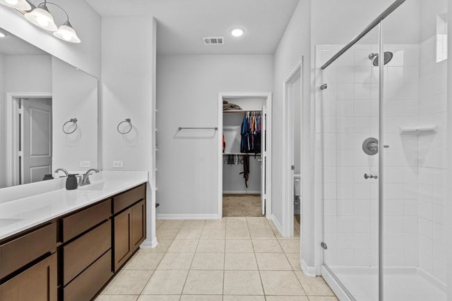 Bathroom with a stall shower, double vanity, a walk in closet, and baseboards | Image 22
