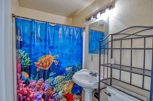 Bathroom with a textured wall, a textured ceiling, toilet, and a shower with curtain | Image 15