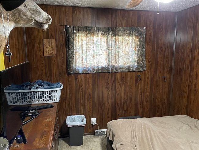 Carpeted bedroom with ceiling fan, a textured ceiling, and wooden walls | Image 14
