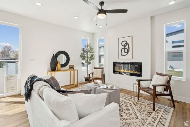 Living area with visible vents, plenty of natural light, a glass covered fireplace, and ceiling fan | Image 4