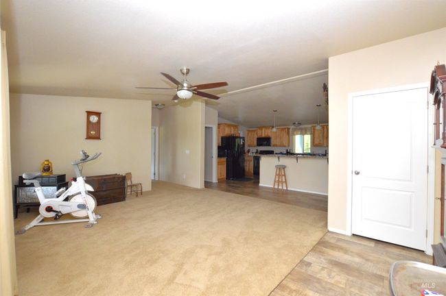 Unfurnished living room featuring ceiling fan, light wood-style floors, vaulted ceiling, and light carpet | Image 13