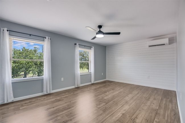 Empty room with a wall unit AC, wood finished floors, a ceiling fan, and wood walls | Image 19