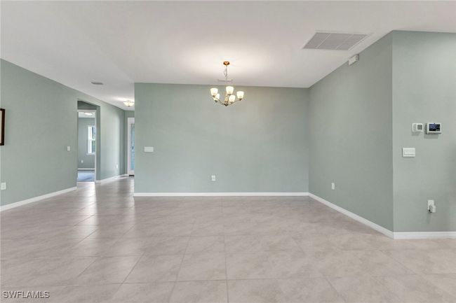 Unfurnished Dining/Living room featuring visible vents, baseboards, a notable chandelier, and light tile patterned flooring | Image 20