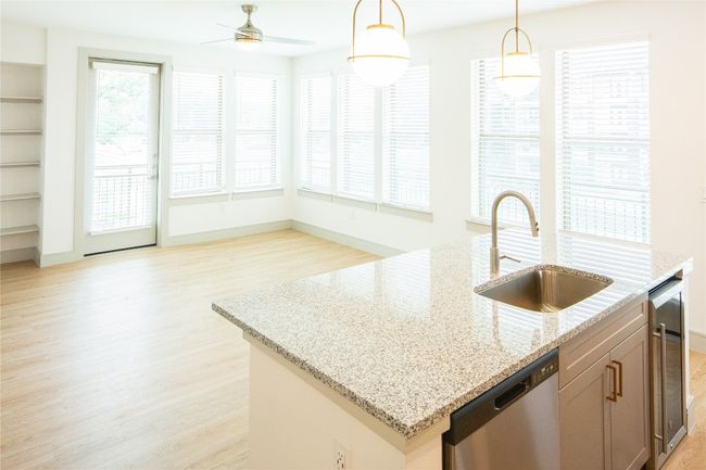 Kitchen with light wood finished floors, a center island with sink, light stone countertops, stainless steel dishwasher, and a sink | Image 15