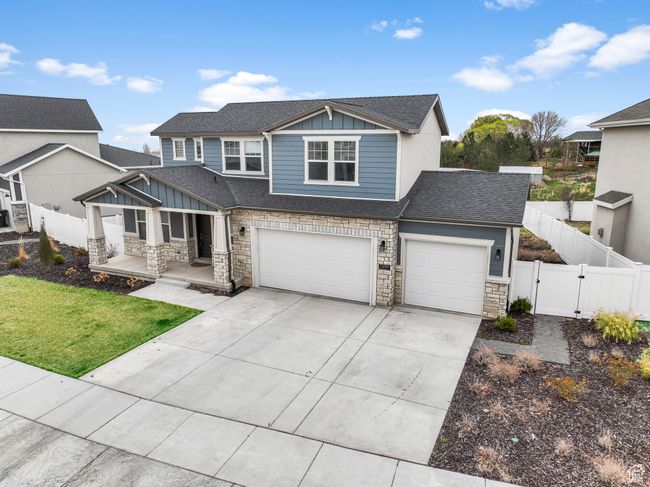 View of front of home with fence, a gate, stone siding, and board and batten siding | Image 25