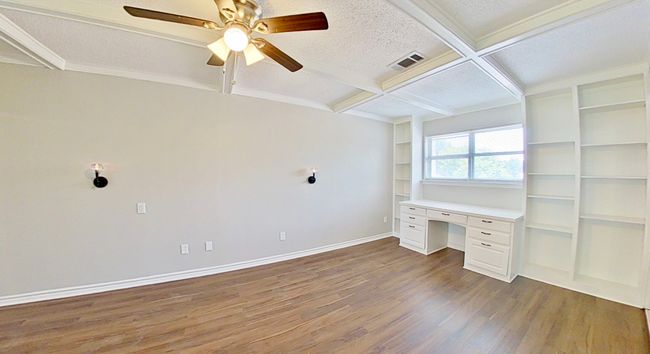 Unfurnished office featuring built in desk, dark wood-style floors, coffered ceiling, visible vents, and beamed ceiling | Image 13