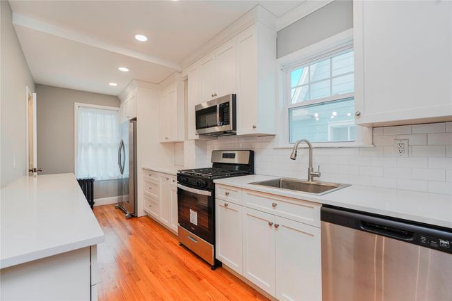 Kitchen featuring a sink, white cabinets, light wood finished floors, and stainless steel appliances | Image 14