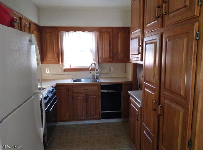 Kitchen featuring white appliances, sink, and tile floors | Image 6