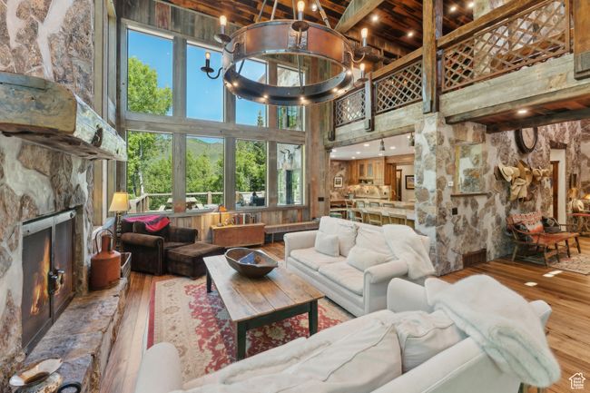 Living room featuring hardwood / wood-style flooring, a towering ceiling, a fireplace, beamed ceiling, and a chandelier | Image 4