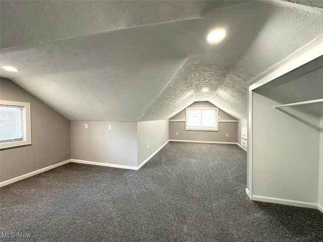 Additional living space with dark colored carpet, a textured ceiling, vaulted ceiling, and baseboards | Image 9