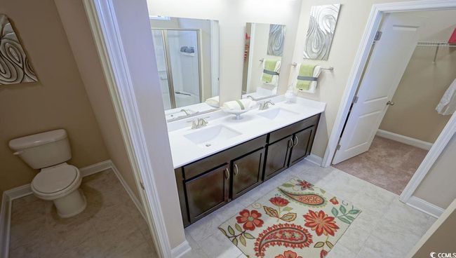 Full bathroom featuring a shower stall, toilet, double vanity, and baseboards | Image 25