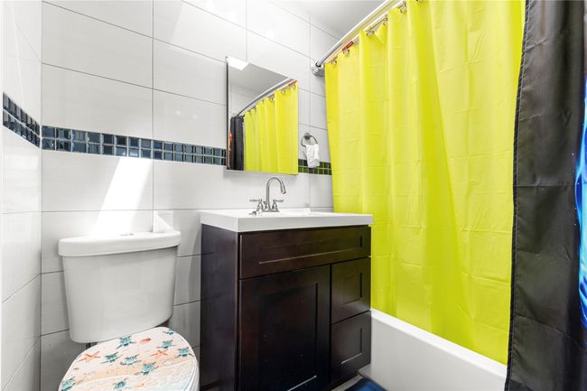 Bathroom featuring tile walls, vanity, toilet, and shower / bath combination with curtain | Image 8