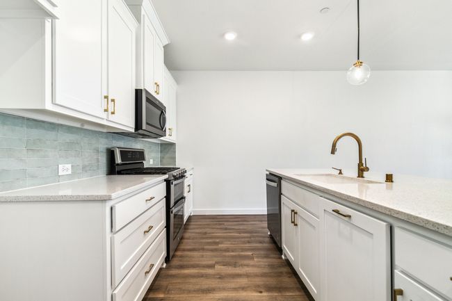 Kitchen featuring stainless steel appliances, a sink, decorative backsplash, white cabinets, and dark wood-type flooring | Image 14