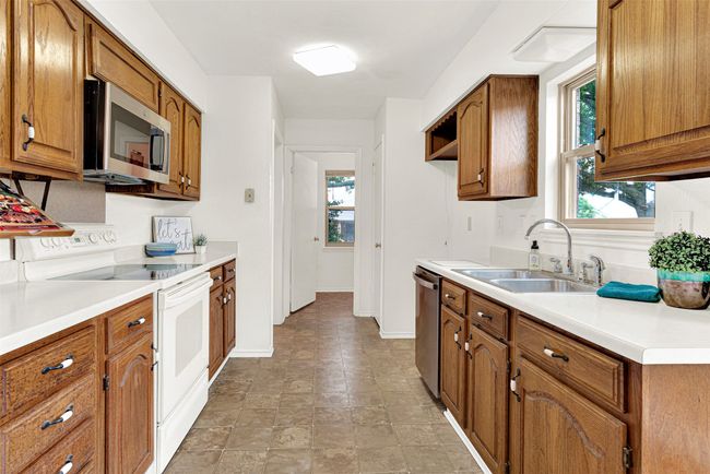 Kitchen with stainless steel appliances, brown cabinetry, light countertops, and stone finish flooring | Image 29