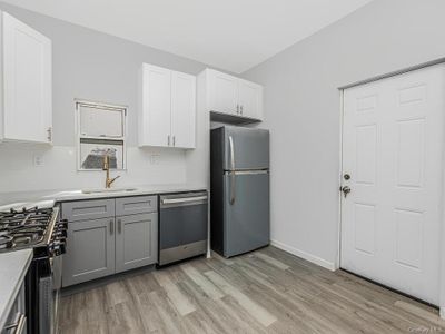 Kitchen with gray cabinetry, backsplash, light wood-type flooring, appliances with stainless steel finishes, and white cabinetry | Image 3