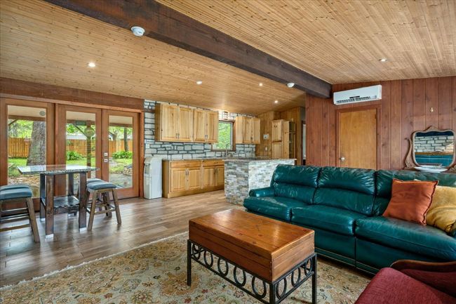 Living room featuring light wood-style flooring, wooden walls, a wall mounted air conditioner, wooden ceiling, and french doors | Image 8