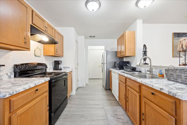 Kitchen featuring black electric range oven, under cabinet range hood, dishwasher, and light wood finished floors | Image 4