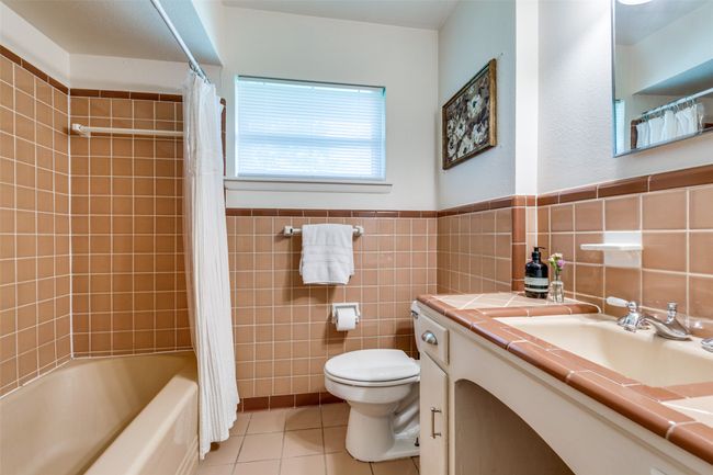 Bathroom with tile flooring, vanity, tile walls, shower / bath combo, and wainscoting | Image 17