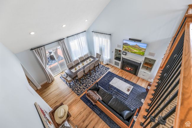 Living area featuring high vaulted ceiling, a glass covered fireplace, baseboards, and wood finished floors | Image 17