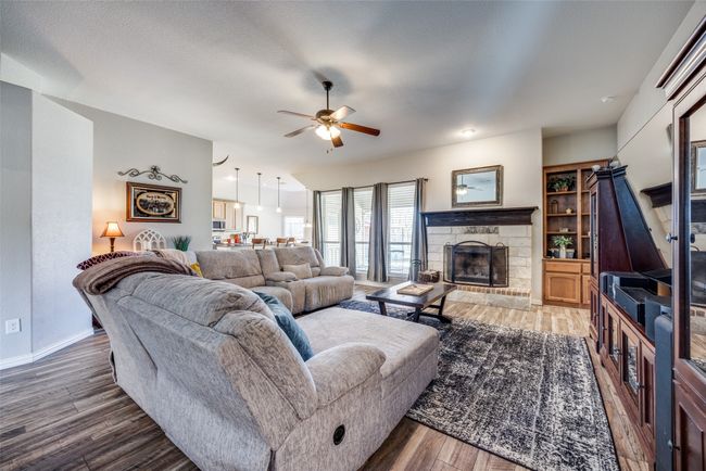 Living room featuring ceiling fan, wood-type flooring, and a fireplace | Image 9