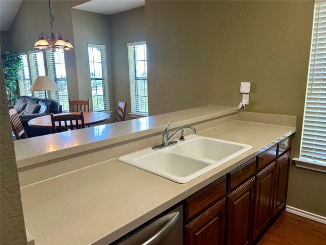 Kitchen featuring a sink, a textured wall, dark wood-style flooring, a chandelier, and light countertops | Image 11
