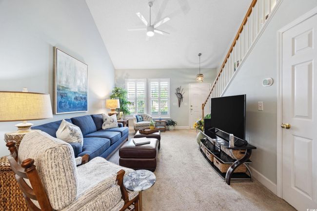 Carpeted living room with ceiling fan, stairway, and high vaulted ceiling | Image 8