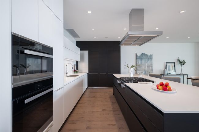 Kitchen featuring modern cabinets, island range hood, a center island, light countertops, and white cabinets | Image 17