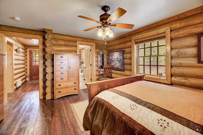 Bedroom with dark wood-style floors, log walls, and ensuite bath | Image 19