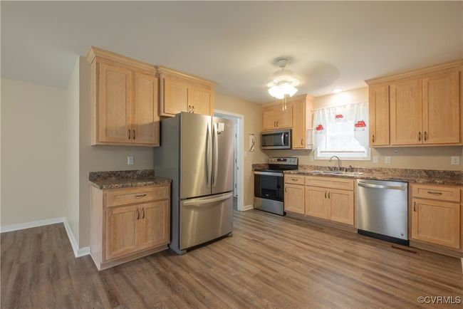 Kitchen with a sink, light brown cabinets, appliances with stainless steel finishes, and wood finished floors | Image 9