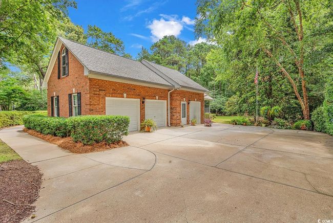 View of side of home with brick siding, driveway, roof with shingles, and an attached garage | Image 34