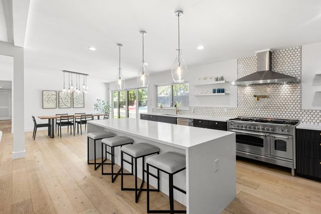 Kitchen featuring tasteful backsplash, a sink, wall chimney range hood, light countertops, and stainless steel appliances | Image 12