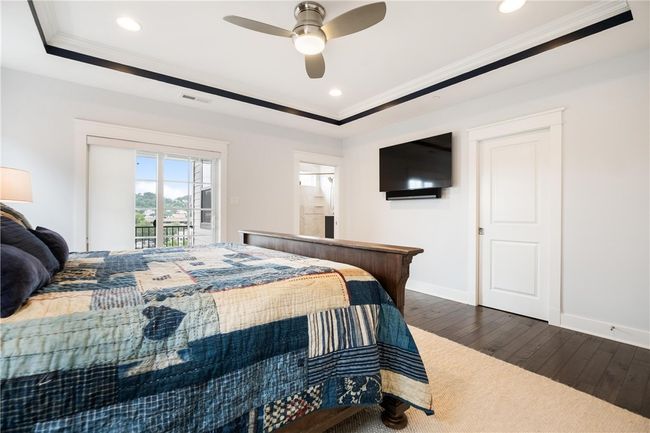 Spacious Owner's Suite on second floor has hardwood floor, 2 walk-in closets (larger one has chandelier!), ceiling fan/light, private luxury bath and sliding door to private covered deck. | Image 19